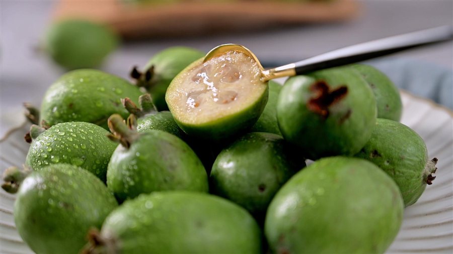 Scooping a feijoa with a spoon Fresh feijoa cut in half with a spoon scooping the flesh