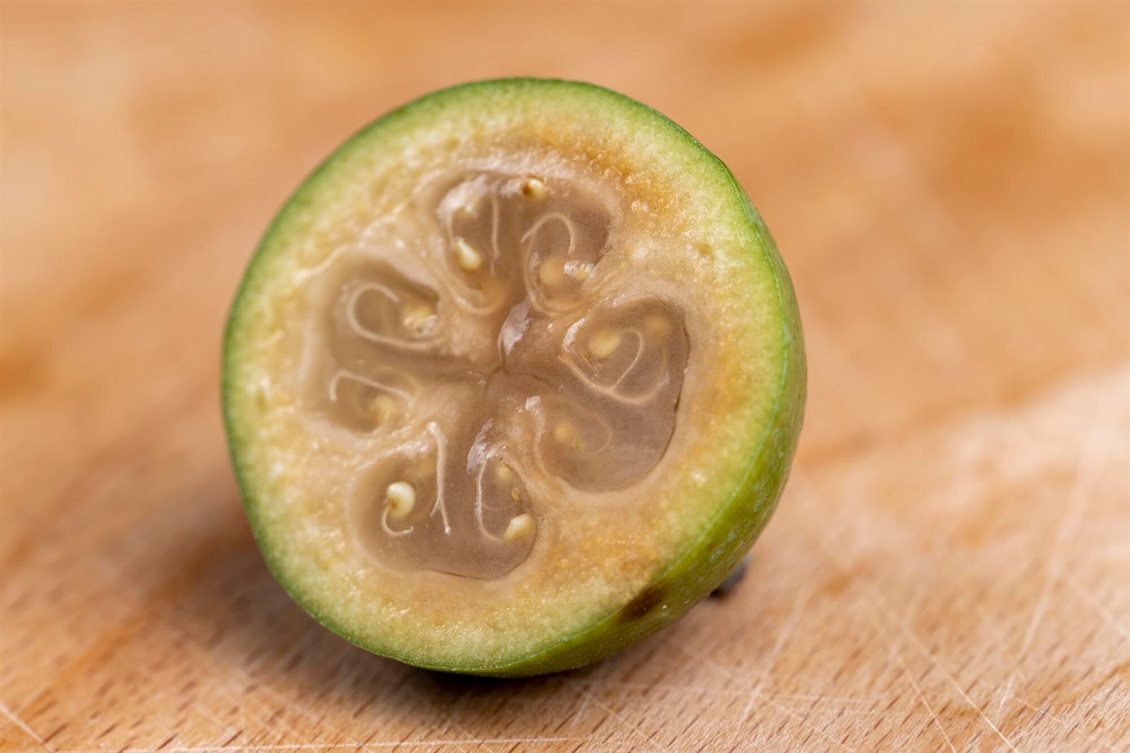 Green ripe feijoa cut in half, showing the flesh and seed cavity