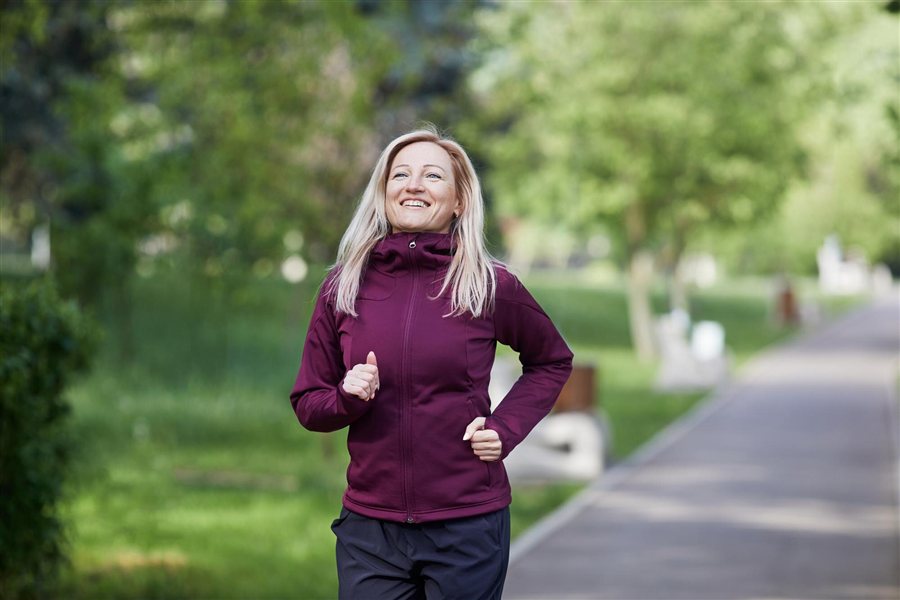 Woman running in a park Smiling middle-aged woman running in a park